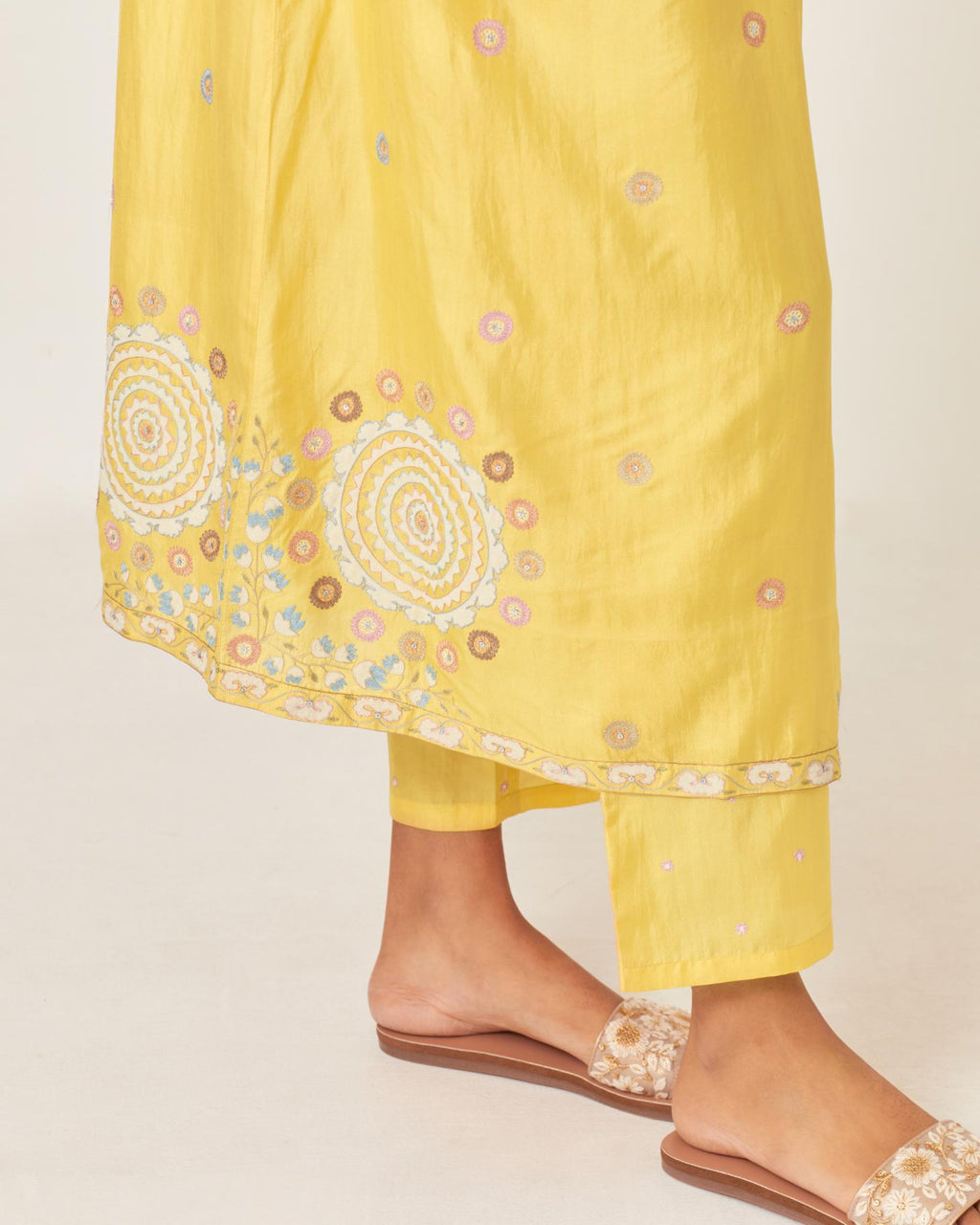 Yellow silk kurta dress set with appliqué stripes along with aari threadwork flowers and floral trellises along with a circular appliqued motif and fine gathers at empire line.