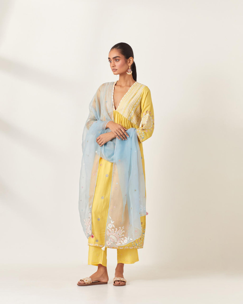 Yellow silk kurta dress set with appliqué stripes along with aari threadwork flowers and floral trellises along with a circular appliqued motif and fine gathers at empire line.