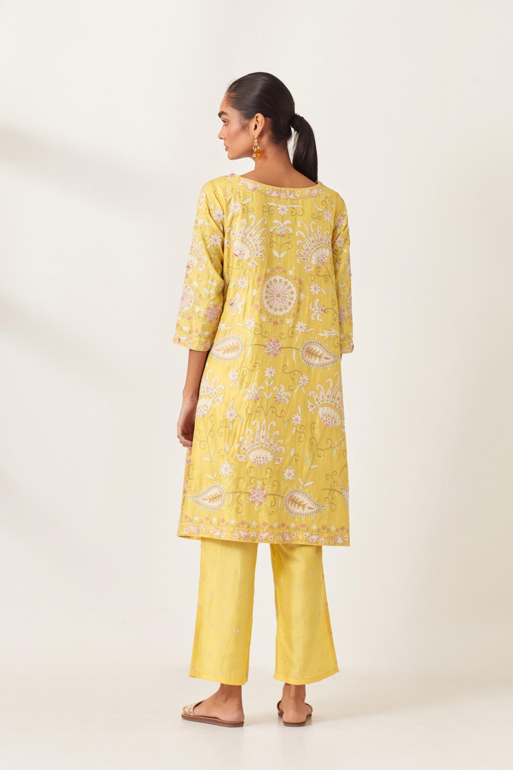 Yellow short A-line silk kurta set, fully embroidered with multi colored appliqué with aari thread work and silk tassels.