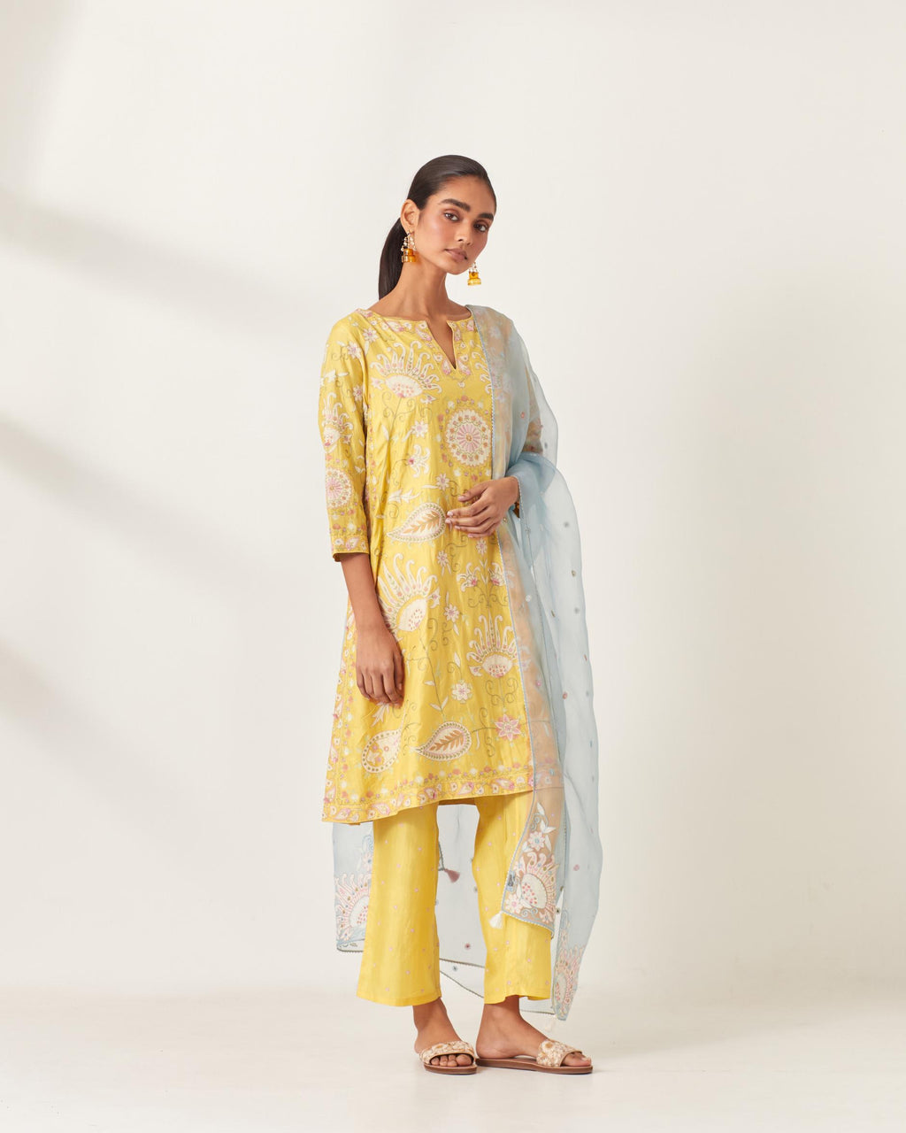 Yellow short A-line silk kurta set, fully embroidered with multi colored appliqué with aari thread work and silk tassels.