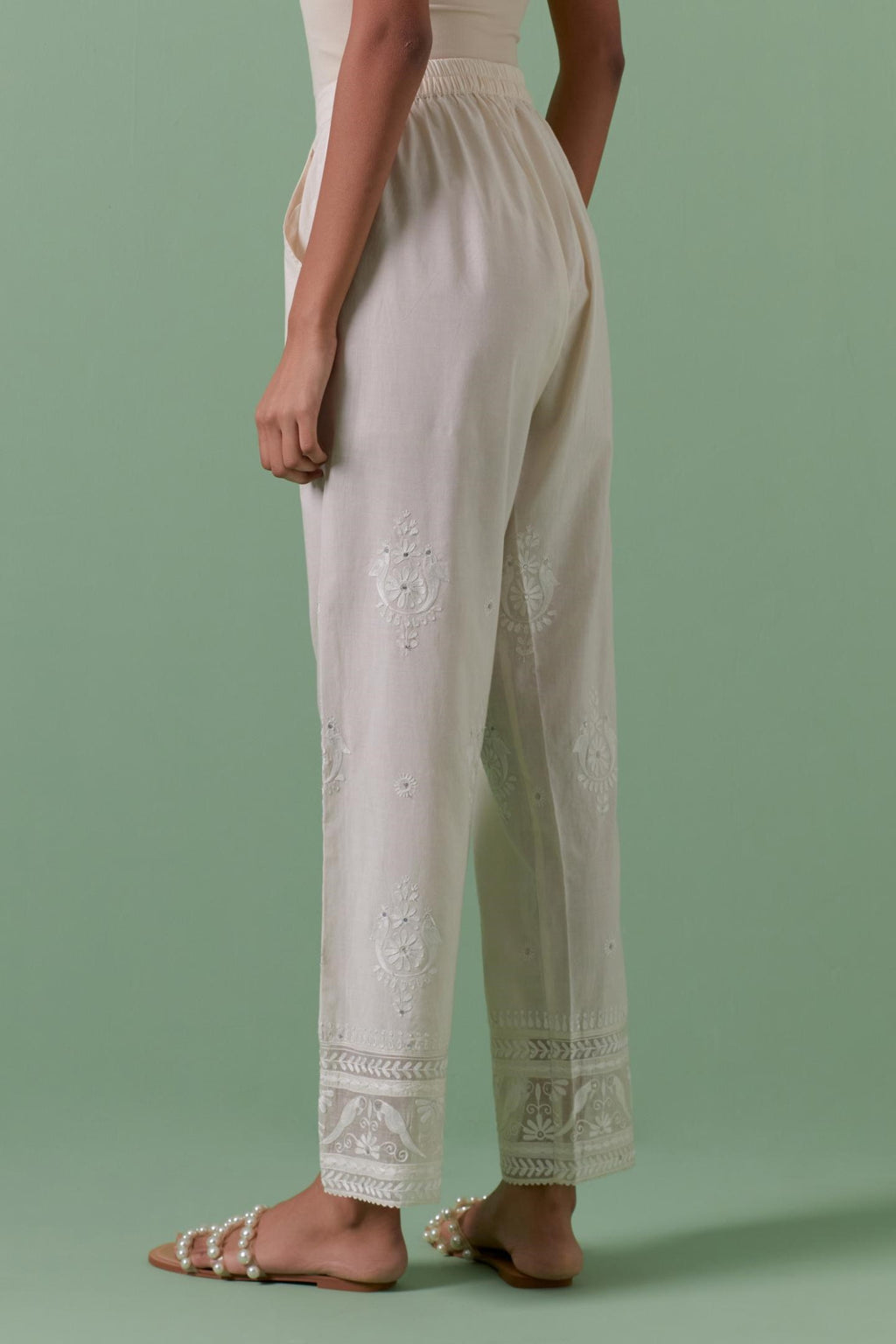 Off white cotton straight pants with all over off white silk thread embroidery detailed with sequins.