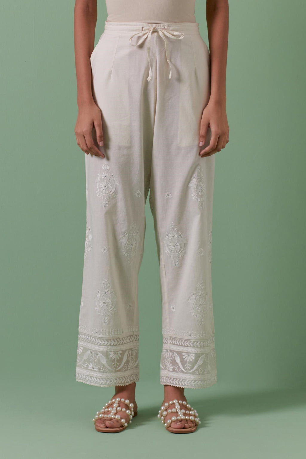 Off white cotton straight pants with all over off white silk thread embroidery detailed with sequins.