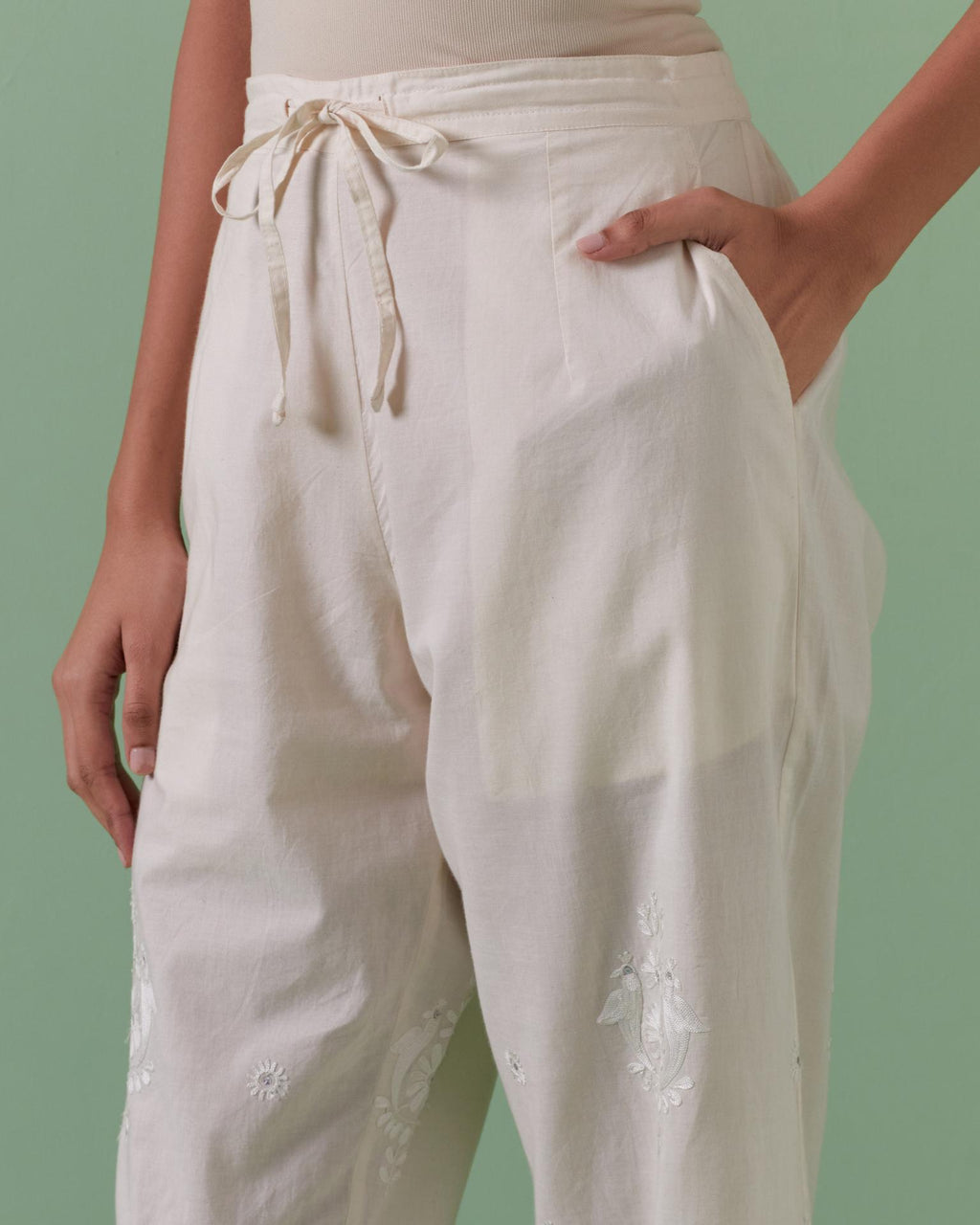 Off white cotton straight pants with all over off white silk thread embroidery detailed with sequins.