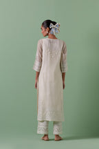 Off-white cotton chanderi straight kurta set with yoke with patchwork and silk thread embroidery highlighted with mirror, sequins, tassels and braids.
