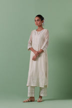 Off-white cotton chanderi straight kurta set with yoke with patchwork and silk thread embroidery highlighted with mirror, sequins, tassels and braids.