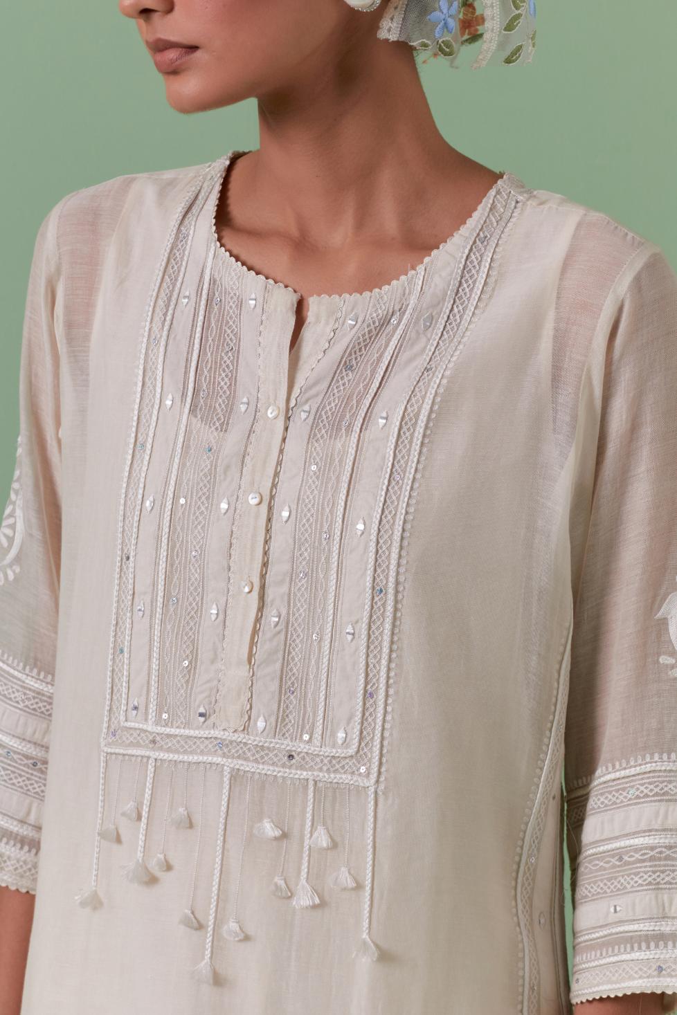 Off-white cotton chanderi straight kurta set with yoke with patchwork and silk thread embroidery highlighted with mirror, sequins, tassels and braids.