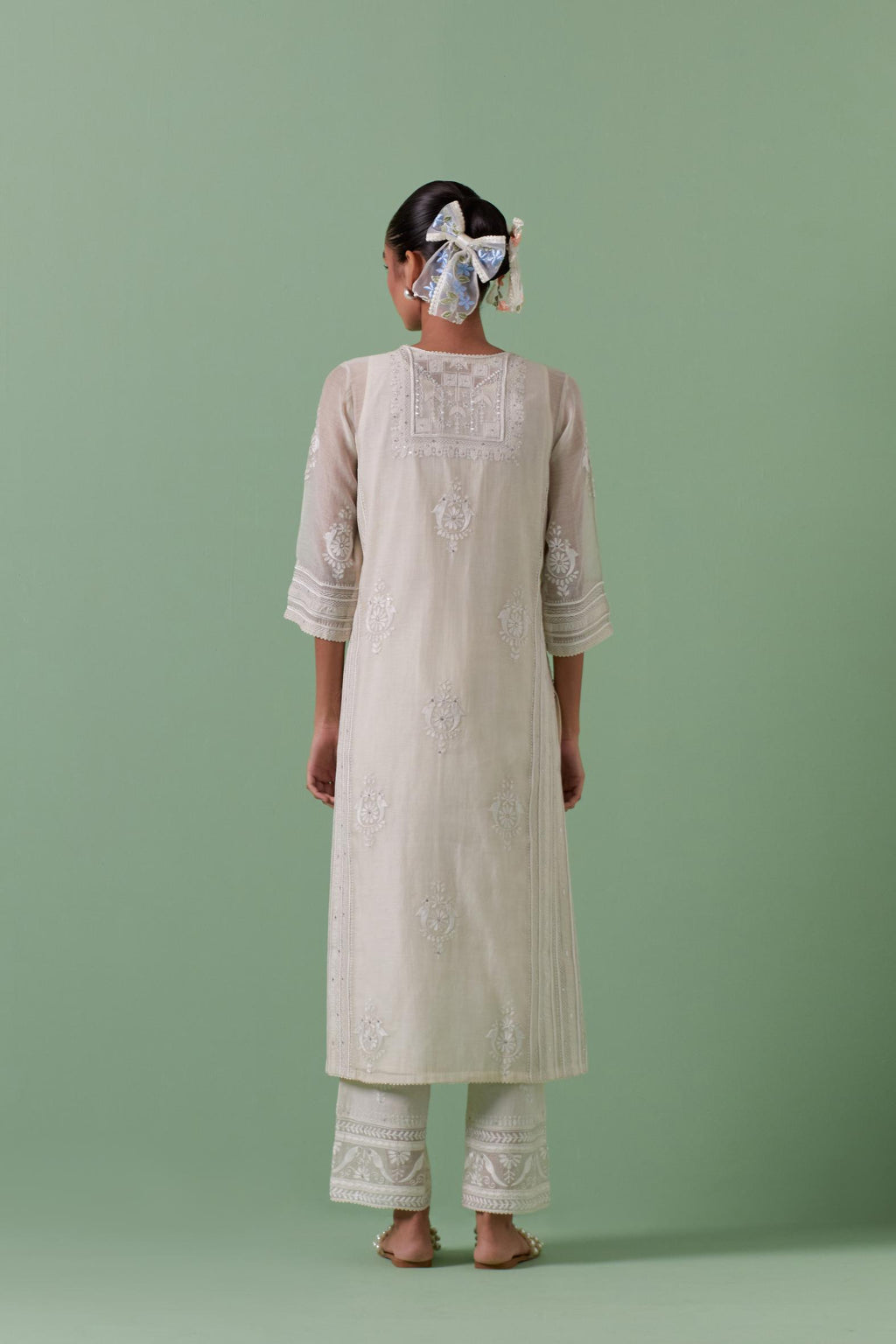 Off-white cotton chanderi straight kurta set with yoke and side panels. It has allover patchwork and silk thread embroidery, highlighted with mirror, sequins, tassels and braids.