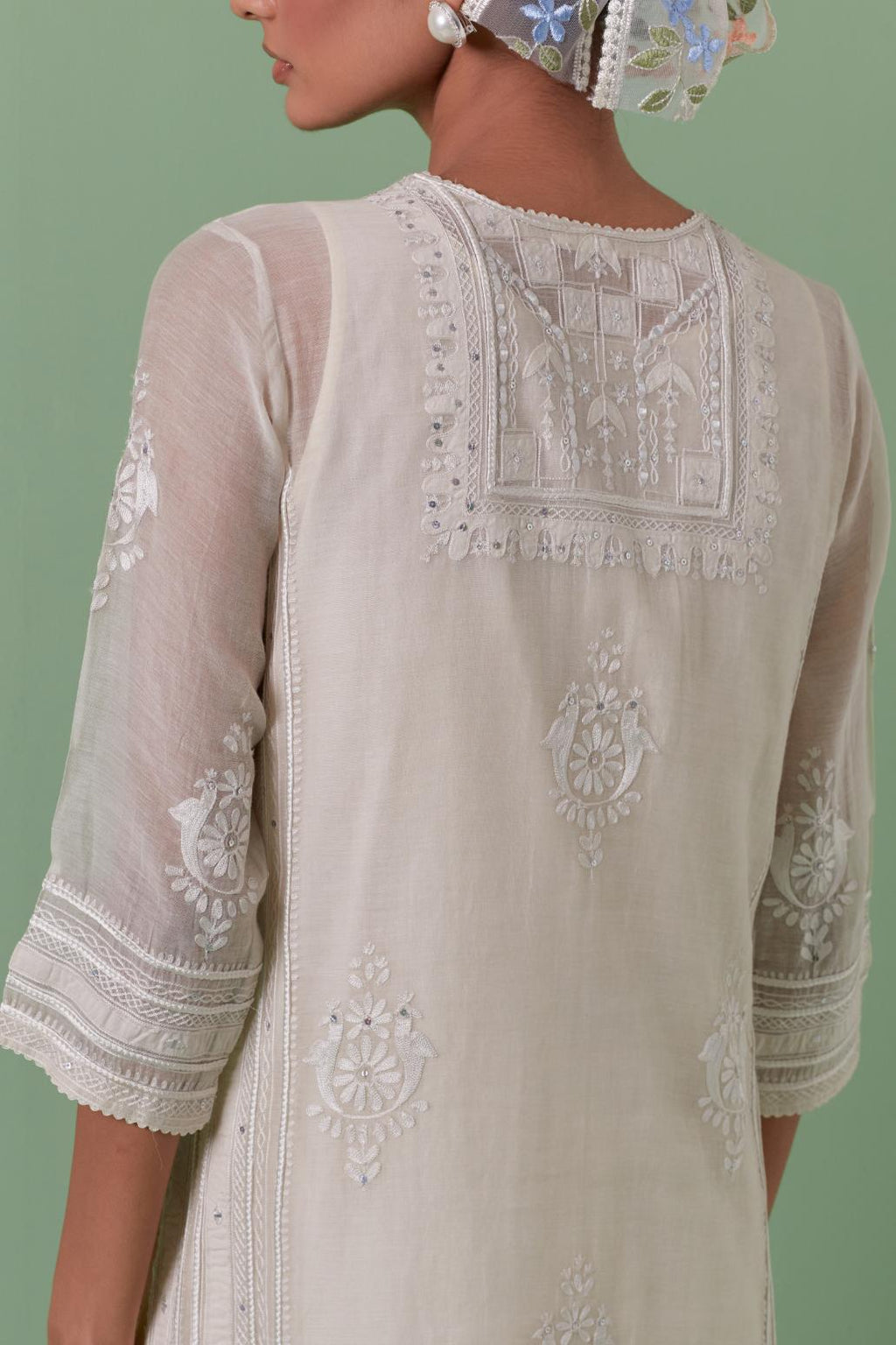 Off-white cotton chanderi straight kurta set with yoke and side panels. It has allover patchwork and silk thread embroidery, highlighted with mirror, sequins, tassels and braids.