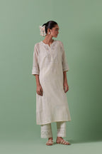 Off-white cotton chanderi straight kurta set with yoke and side panels. It has allover patchwork and silk thread embroidery, highlighted with mirror, sequins, tassels and braids.