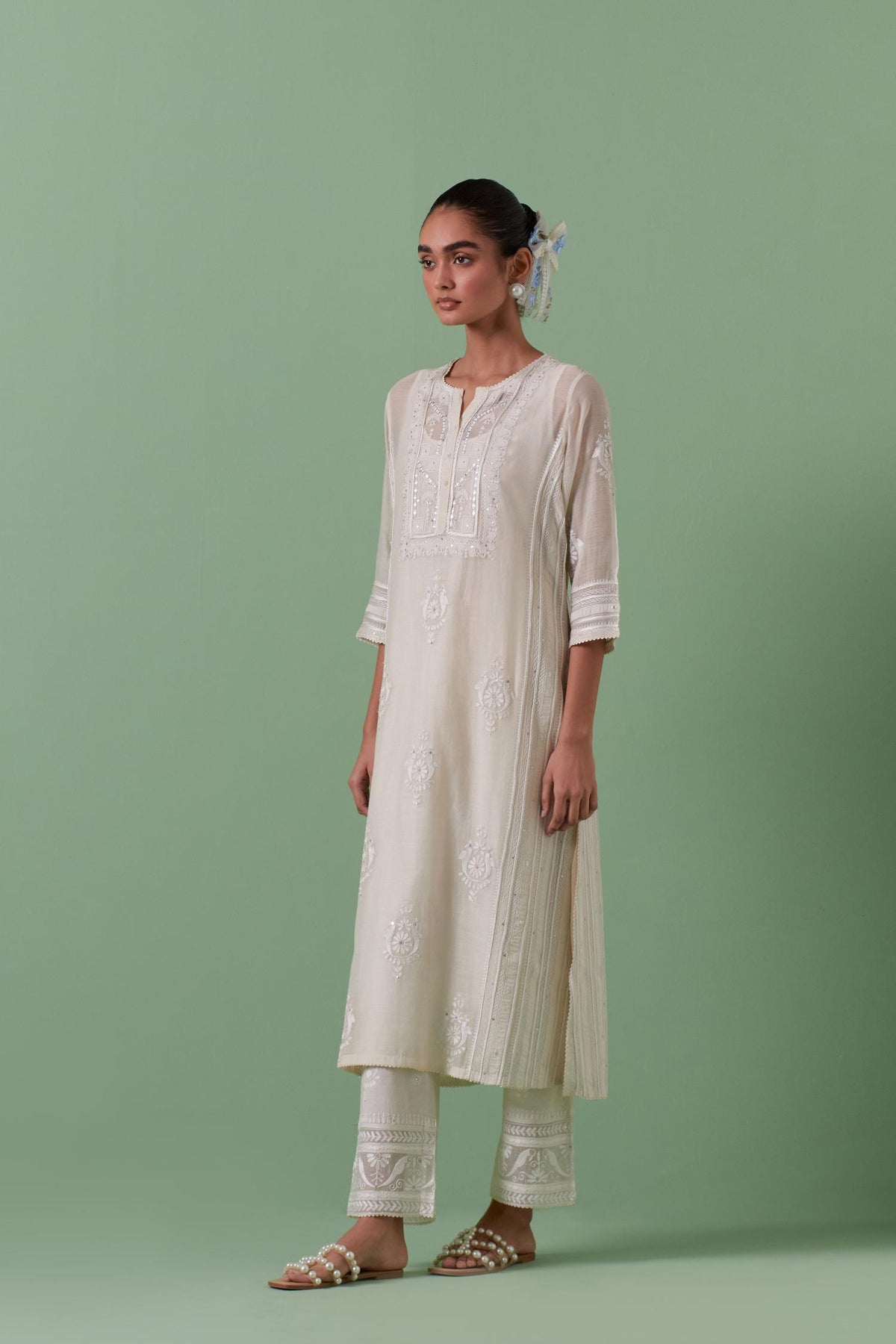 Off-white cotton chanderi straight kurta set with yoke and side panels. It has allover patchwork and silk thread embroidery, highlighted with mirror, sequins, tassels and braids.