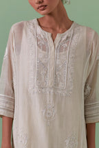 Off-white cotton chanderi straight kurta set with yoke and side panels. It has allover patchwork and silk thread embroidery, highlighted with mirror, sequins, tassels and braids.