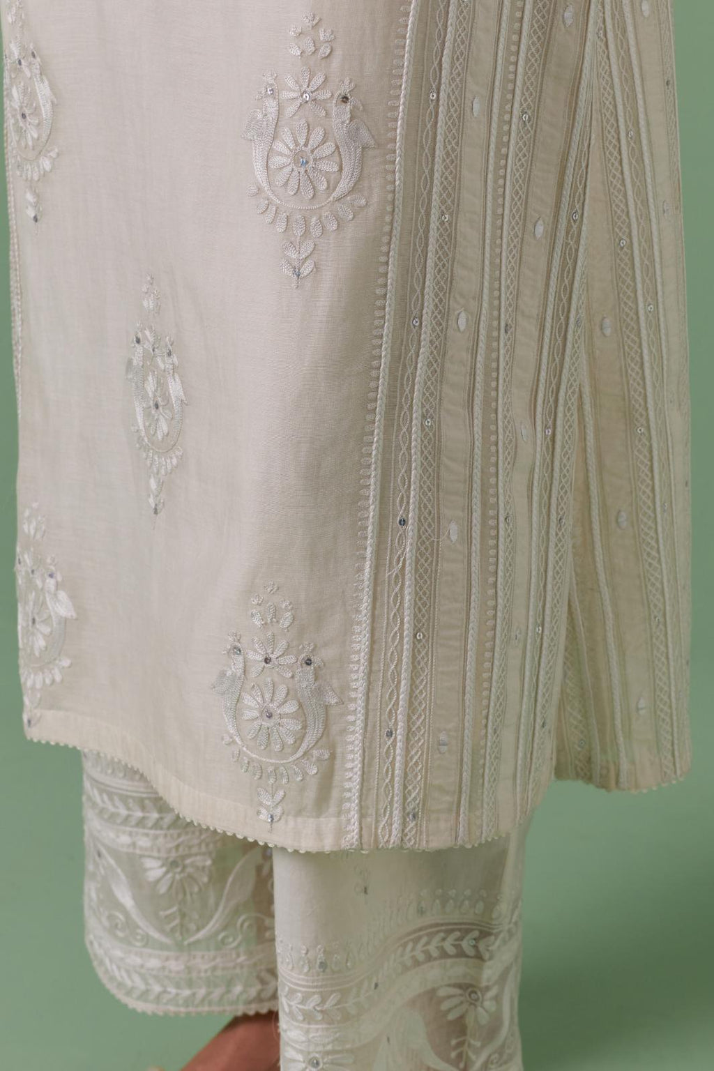 Off-white cotton chanderi straight kurta set with yoke and side panels. It has allover patchwork and silk thread embroidery, highlighted with mirror, sequins, tassels and braids.