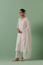 Off-white cotton chanderi straight kurta set with yoke and side panels. It has allover patchwork and silk thread embroidery, highlighted with mirror, sequins, tassels and braids.