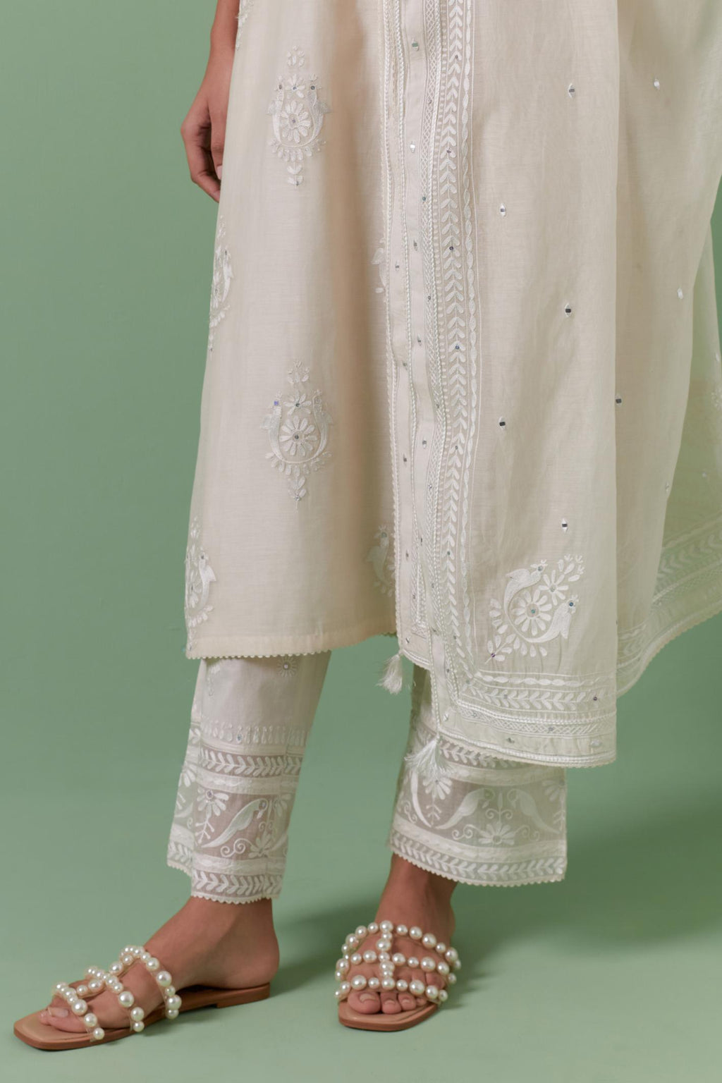 Off-white cotton chanderi straight kurta set with yoke and side panels. It has allover patchwork and silk thread embroidery, highlighted with mirror, sequins, tassels and braids.