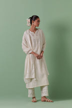 Off-white cotton chanderi straight kurta set with yoke and side panels. It has allover patchwork and silk thread embroidery, highlighted with mirror, sequins, tassels and braids.