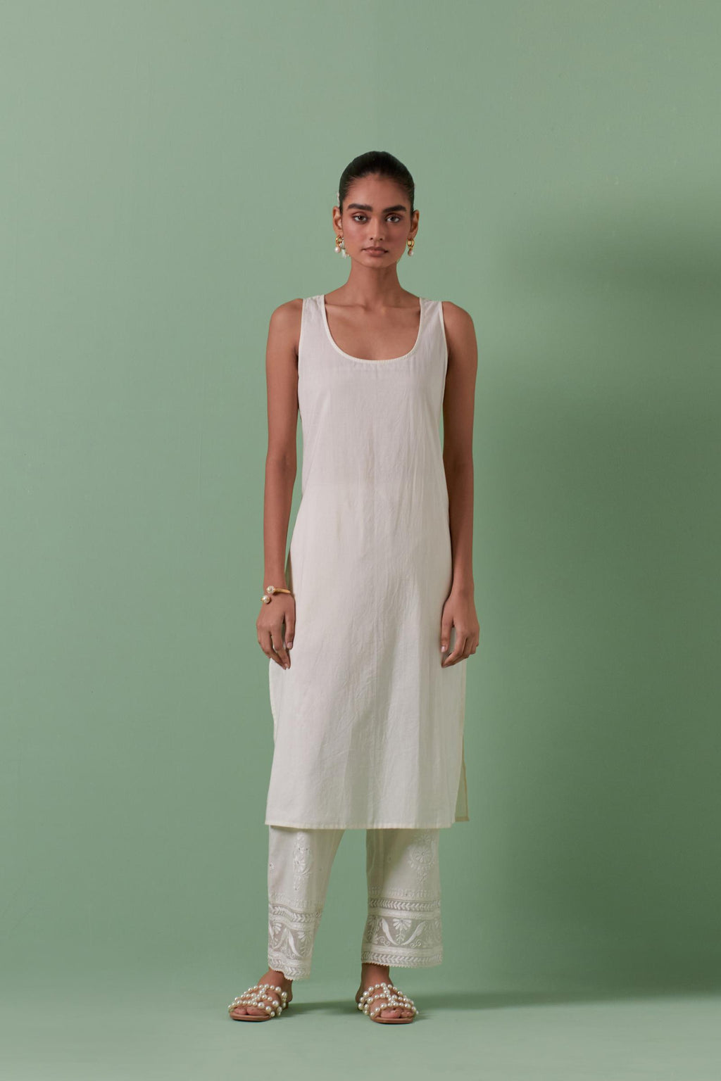 Off-white cotton chanderi straight kurta set with yoke and side panels. It has allover patchwork and silk thread embroidery, highlighted with mirror, sequins, tassels and braids.