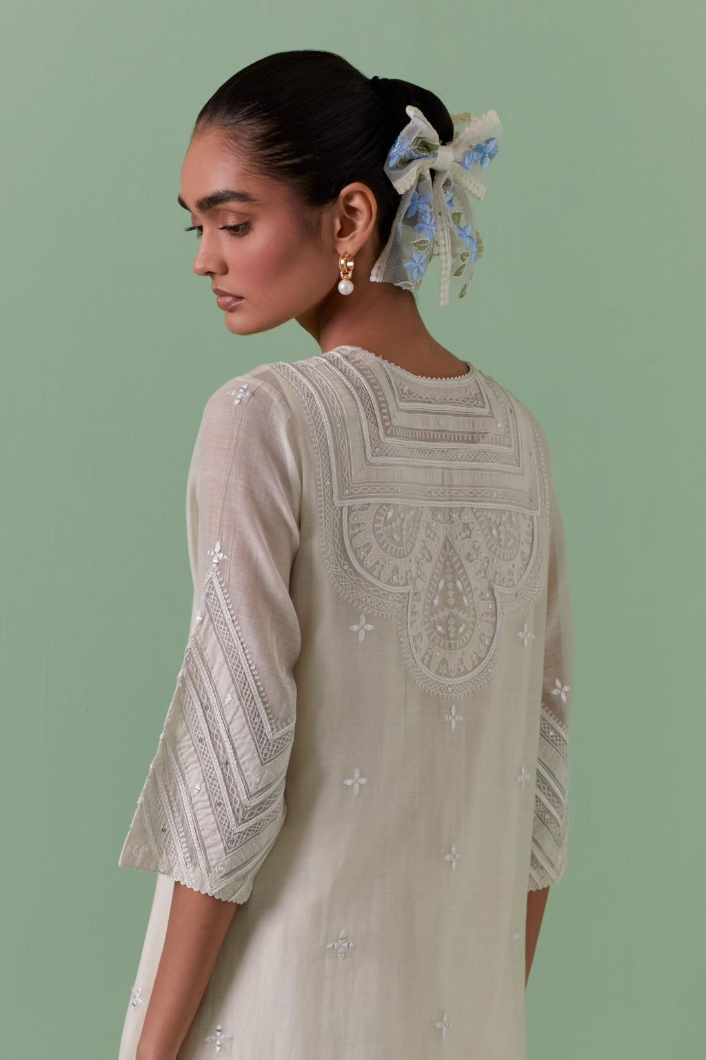 Off-white cotton chanderi straight kurta set with patchwork and thread embroidery highlighted with mirrors, sequins, tassels and braids.
