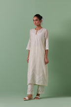 Off-white cotton chanderi straight kurta set with patchwork and thread embroidery highlighted with mirrors, sequins, tassels and braids.