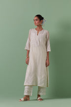 Off-white cotton chanderi straight kurta set with patchwork and thread embroidery highlighted with mirrors, sequins, tassels and braids.