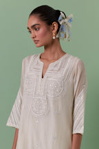 Off-white cotton chanderi straight kurta set with patchwork and thread embroidery highlighted with mirrors, sequins, tassels and braids.