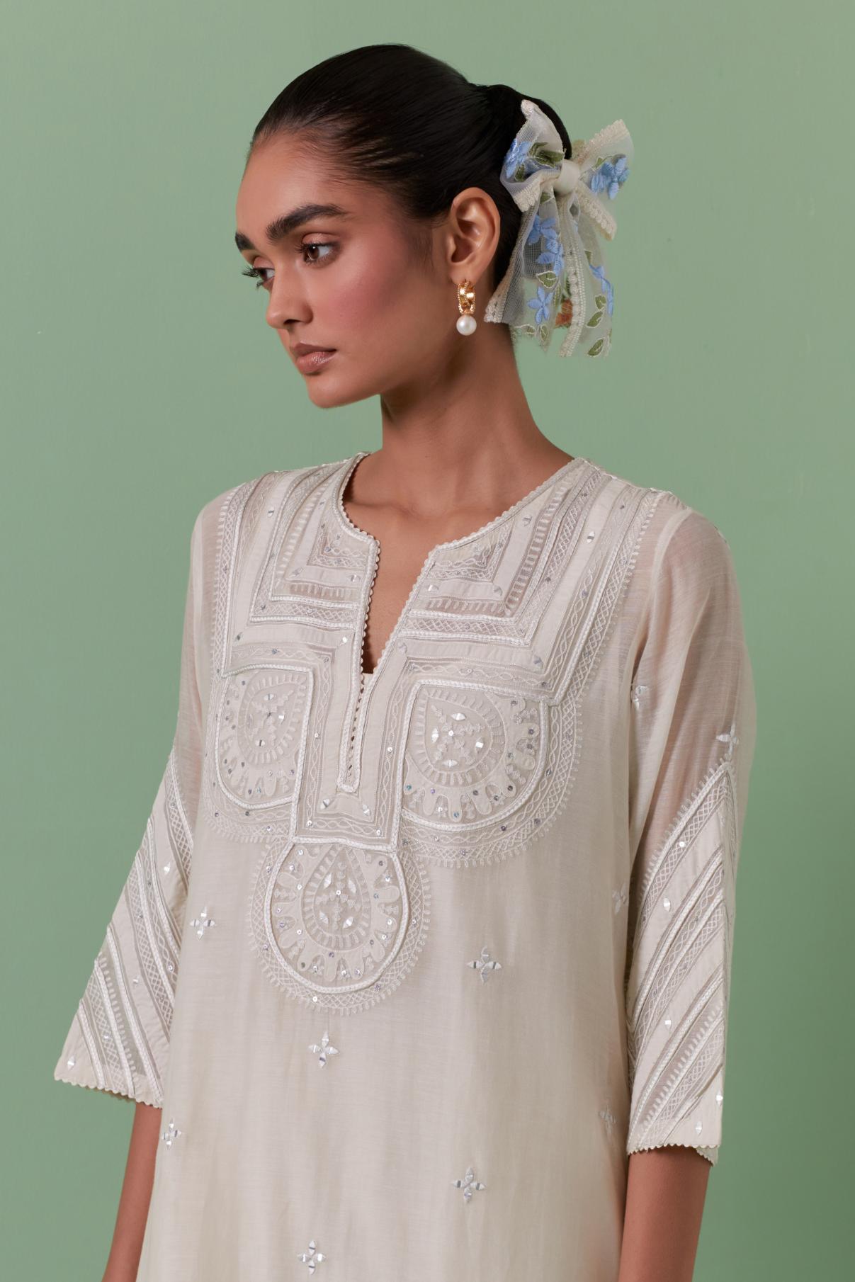Off-white cotton chanderi straight kurta set with patchwork and thread embroidery highlighted with mirrors, sequins, tassels and braids.