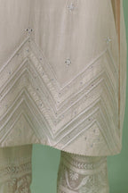 Off-white cotton chanderi straight kurta set with patchwork and thread embroidery highlighted with mirrors, sequins, tassels and braids.