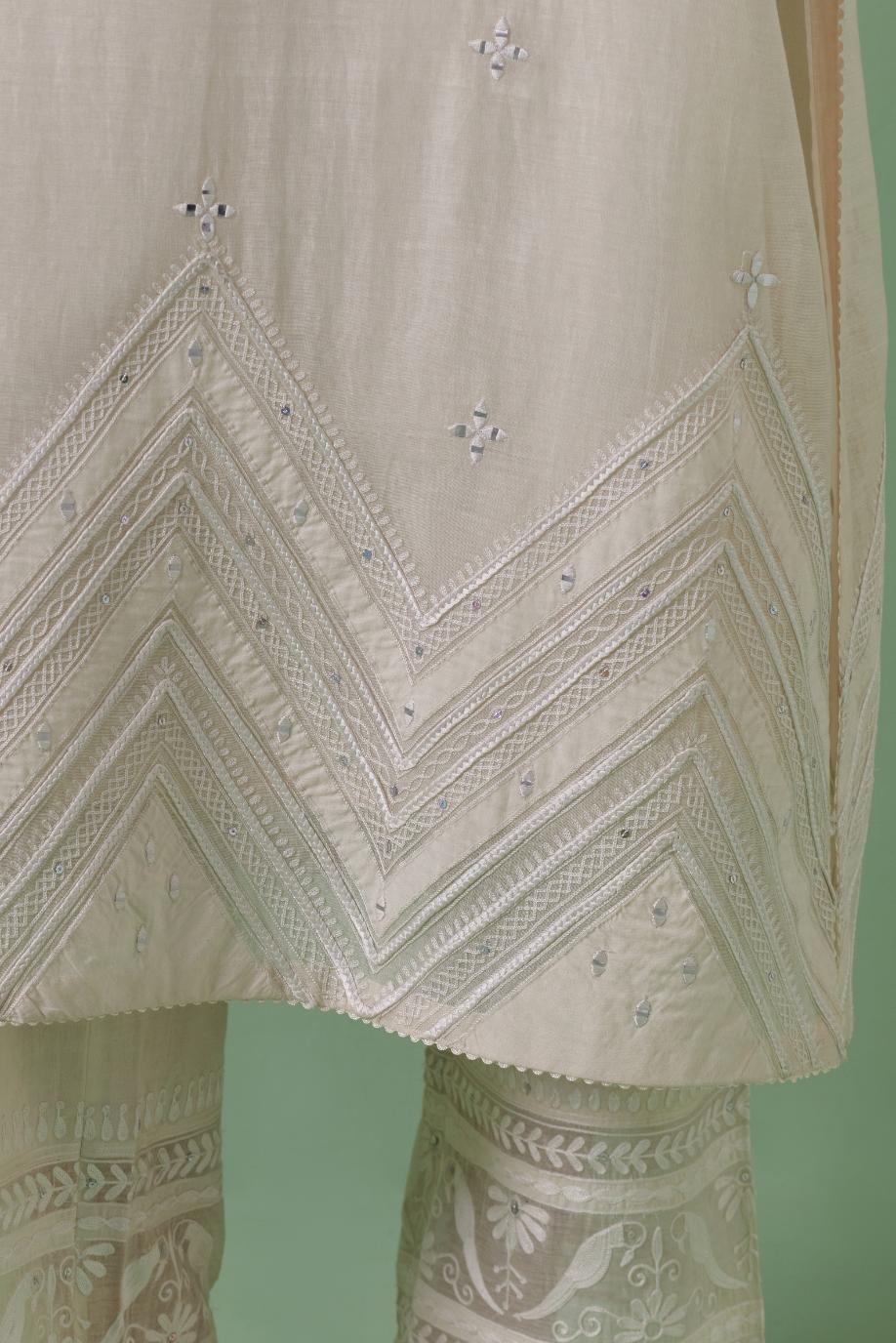 Off-white cotton chanderi straight kurta set with patchwork and thread embroidery highlighted with mirrors, sequins, tassels and braids.
