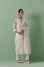 Off-white cotton chanderi straight kurta set with patchwork and thread embroidery highlighted with mirrors, sequins, tassels and braids.