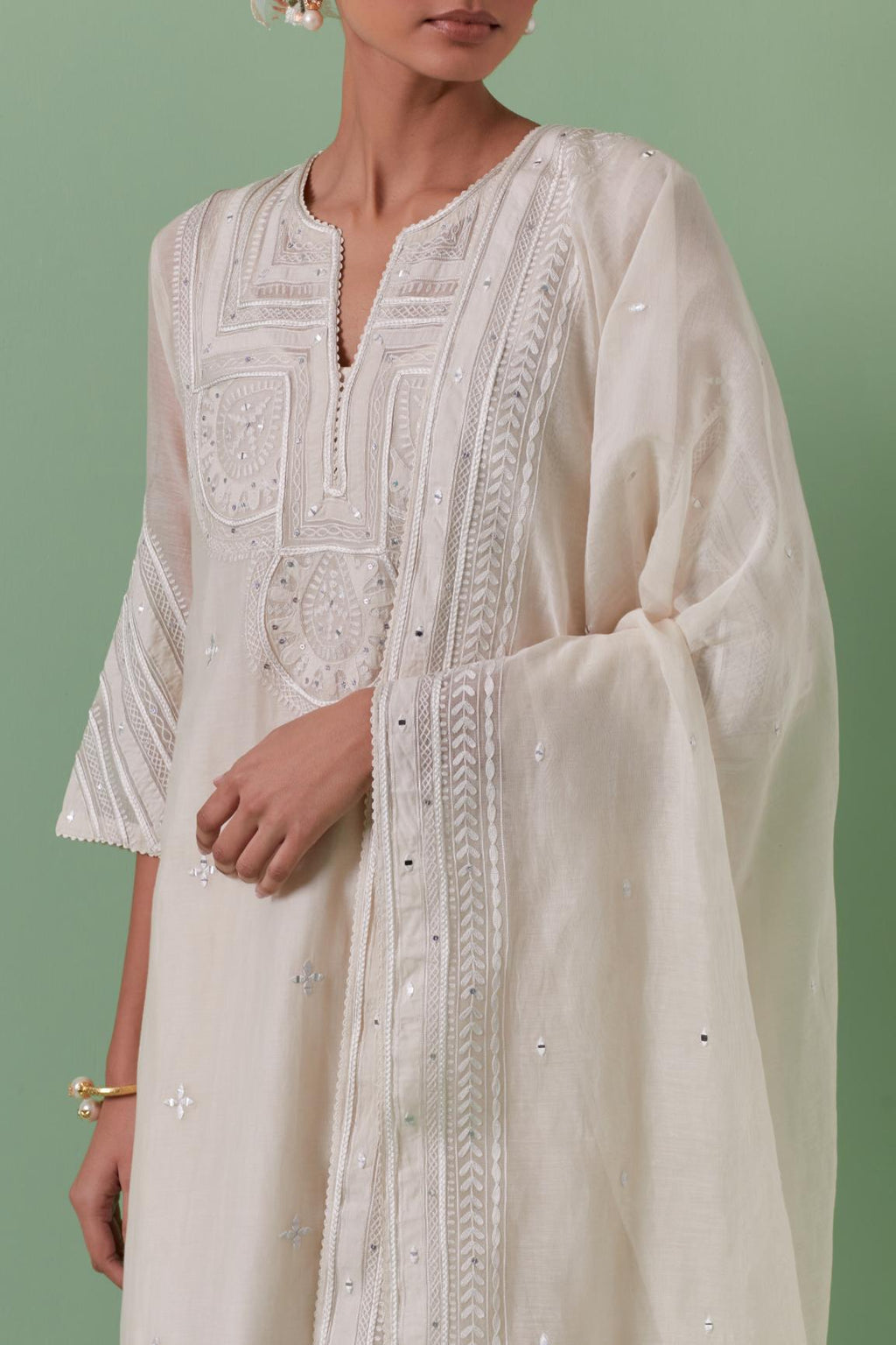 Off-white cotton chanderi straight kurta set with patchwork and thread embroidery highlighted with mirrors, sequins, tassels and braids.