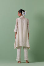 Off white cotton chanderi A-line kurta set with collar, detailed with patchwork, silk thread embroidery, mirrors, sequins and tassels.