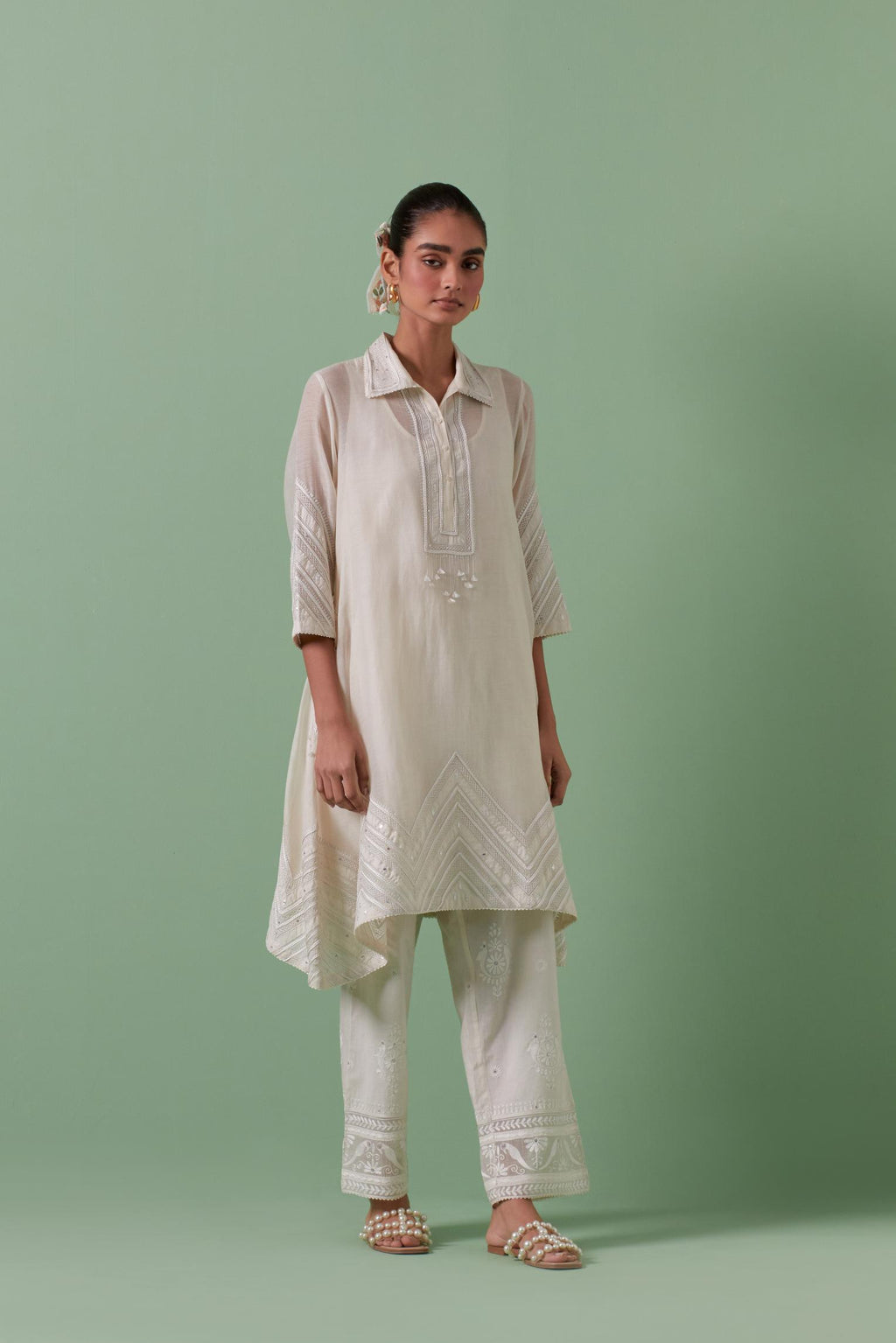 Off white cotton chanderi A-line kurta set with collar, detailed with patchwork, silk thread embroidery, mirrors, sequins and tassels.