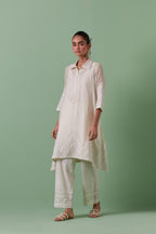 Off white cotton chanderi A-line kurta set with collar, detailed with patchwork, silk thread embroidery, mirrors, sequins and tassels.