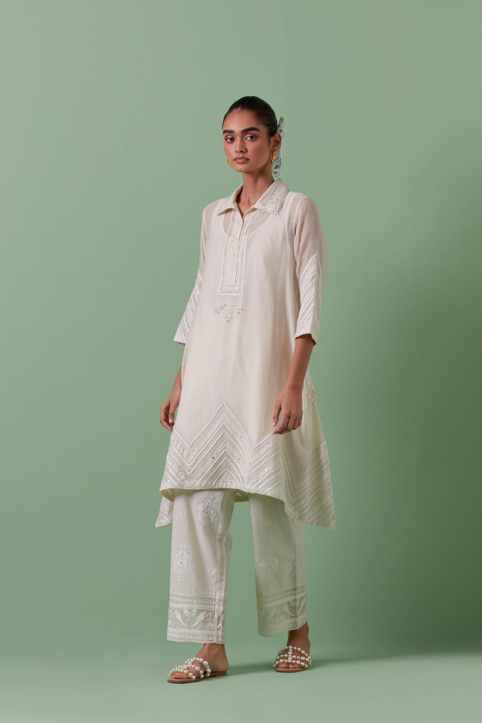Off white cotton chanderi A-line kurta set with collar, detailed with patchwork, silk thread embroidery, mirrors, sequins and tassels.