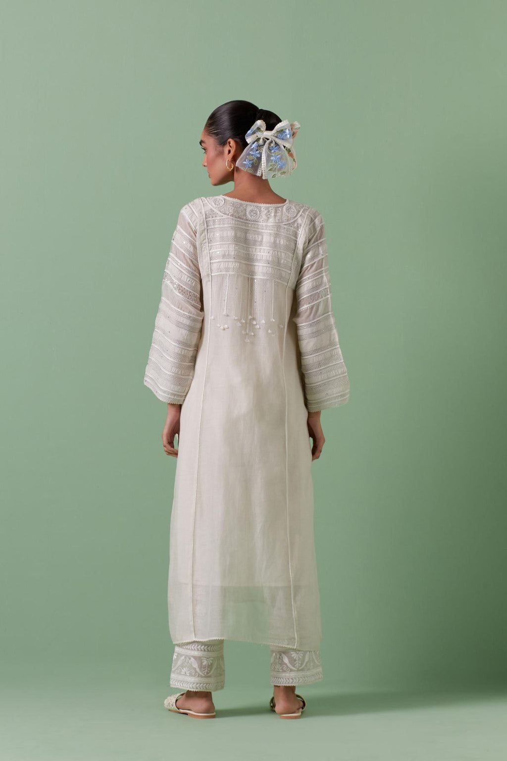 Off-white cotton chanderi easy fit long kaftan detailed with patch, silk thread, mirror & sequins work, paired with off white cotton straight pants with all over off white silk thread embroidery detailed with sequins.