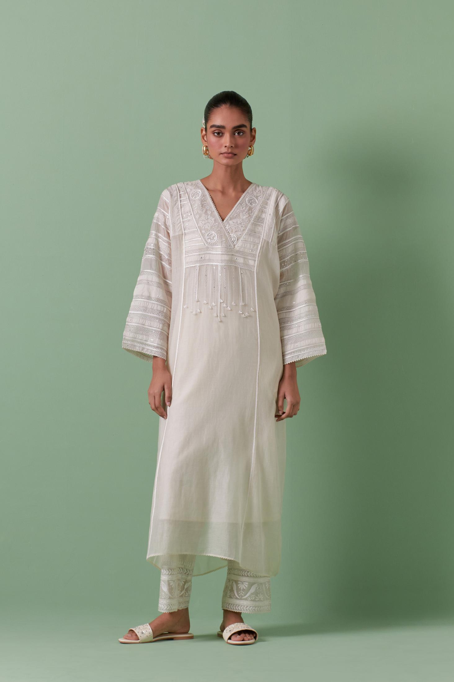 Off-white cotton chanderi easy fit long kaftan detailed with patch, silk thread, mirror & sequins work, paired with off white cotton straight pants with all over off white silk thread embroidery detailed with sequins.