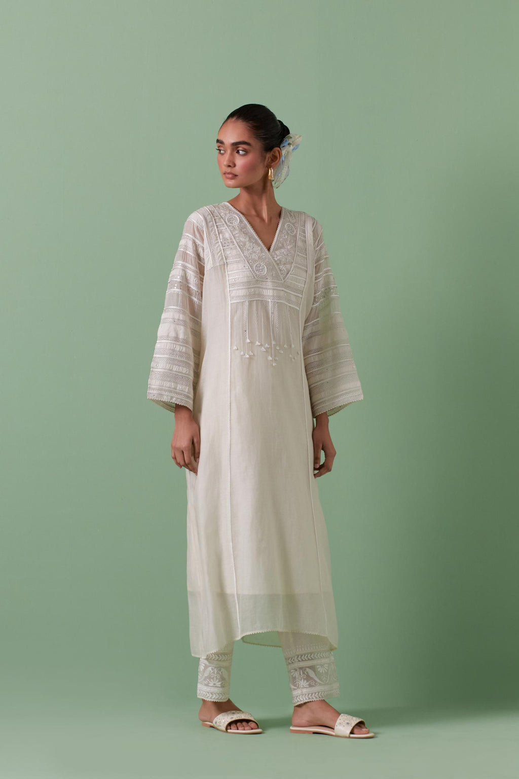 Off-white cotton chanderi easy fit long kaftan detailed with patch, silk thread, mirror & sequins work, paired with off white cotton straight pants with all over off white silk thread embroidery detailed with sequins.