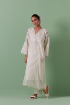 Off-white cotton chanderi easy fit long kaftan detailed with patch, silk thread, mirror & sequins work, paired with off white cotton straight pants with all over off white silk thread embroidery detailed with sequins.