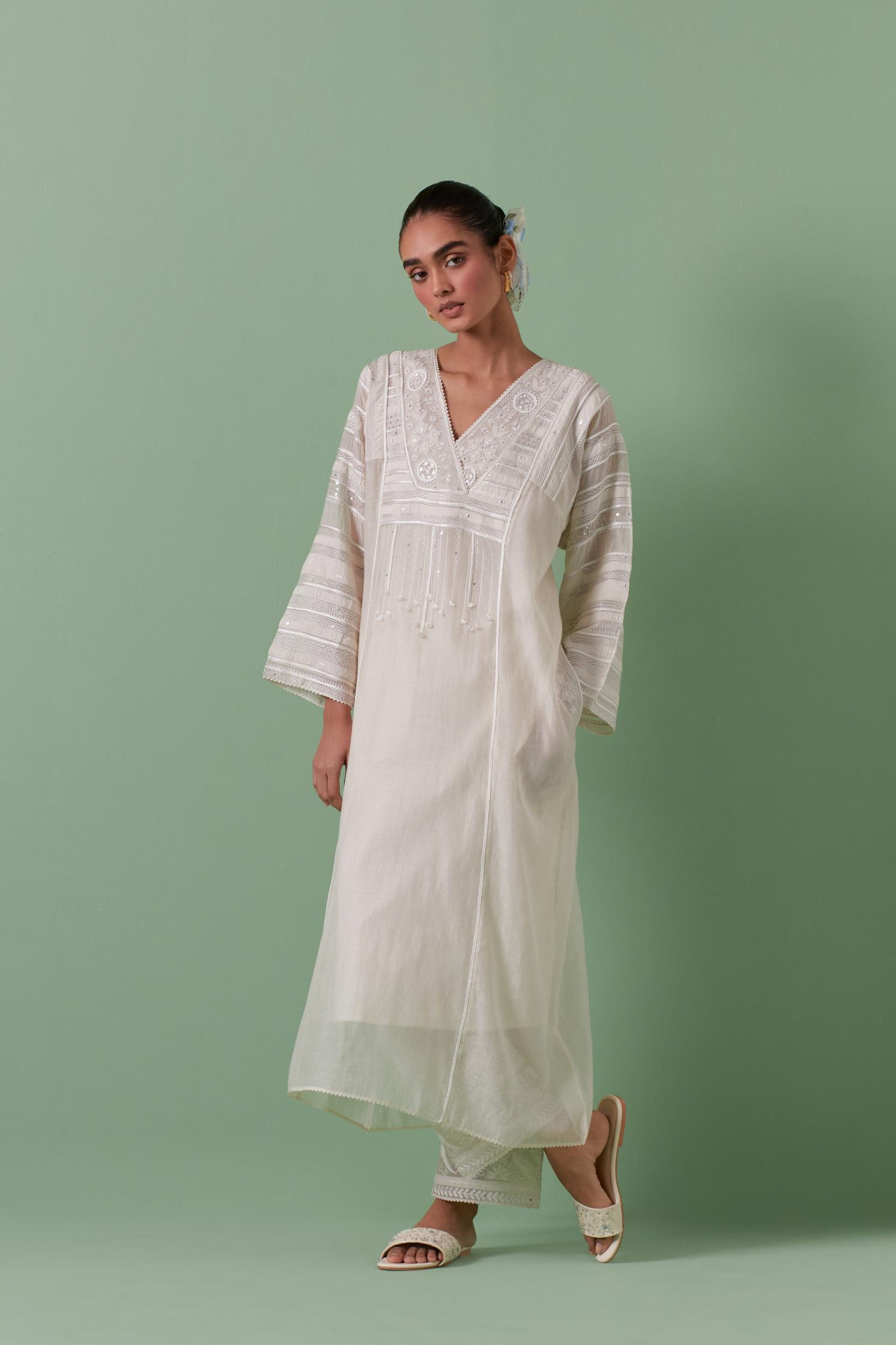 Off-white cotton chanderi easy fit long kaftan detailed with patch, silk thread, mirror & sequins work, paired with off white cotton straight pants with all over off white silk thread embroidery detailed with sequins.