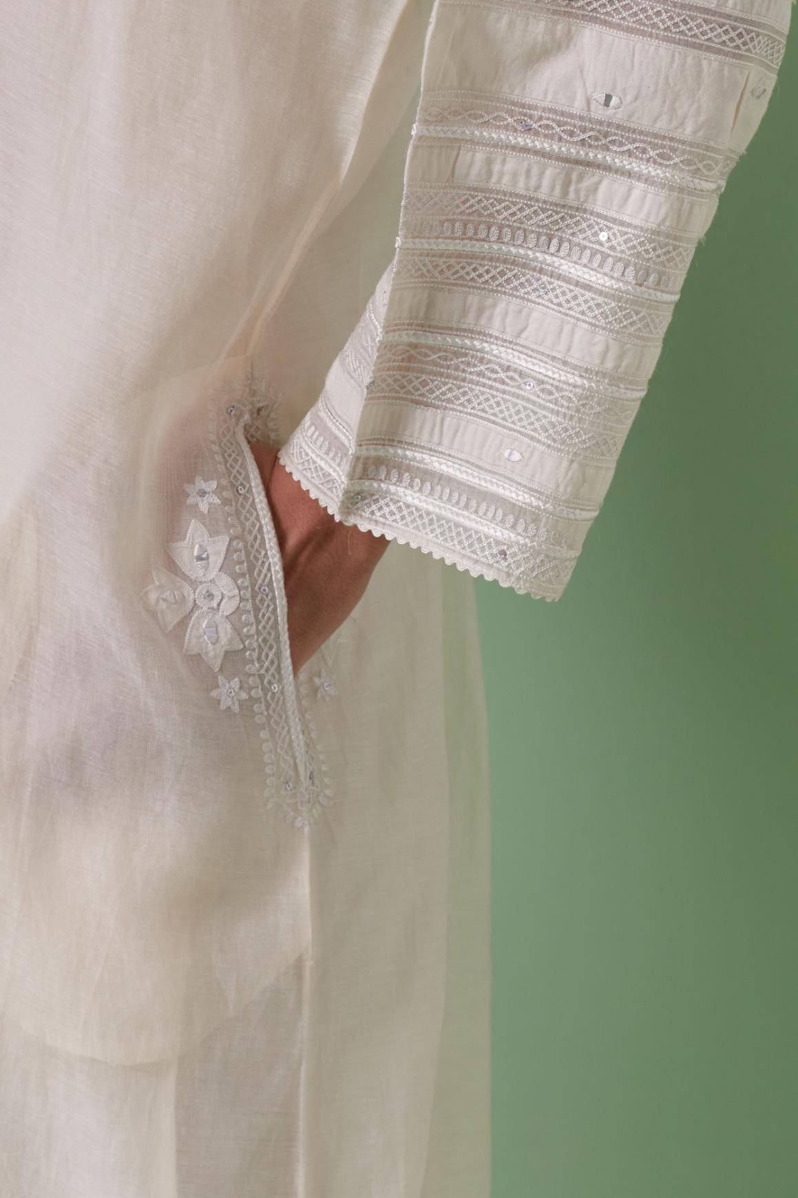 Off-white cotton chanderi easy fit long kaftan detailed with patch, silk thread, mirror & sequins work, paired with off white cotton straight pants with all over off white silk thread embroidery detailed with sequins.