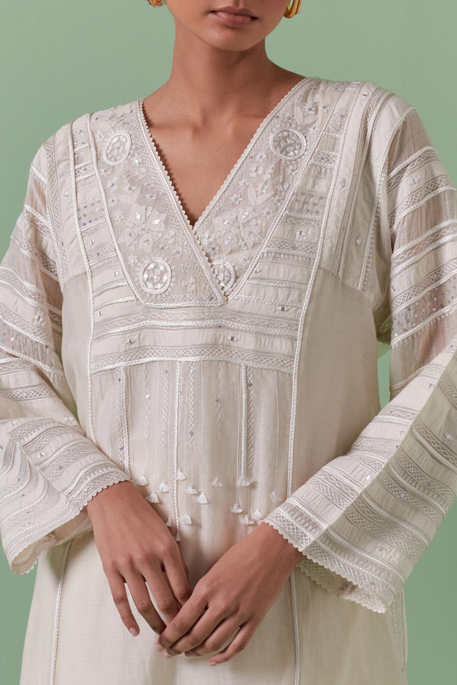 Off-white cotton chanderi easy fit long kaftan detailed with patch, silk thread, mirror & sequins work, paired with off white cotton straight pants with all over off white silk thread embroidery detailed with sequins.