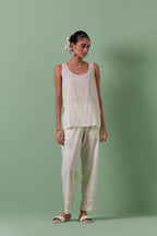 Off-white cotton chanderi embroidered short top with 3/4th sleeves, paired with off white cotton straight pants with all over off white color embroidery detailed with sequins.