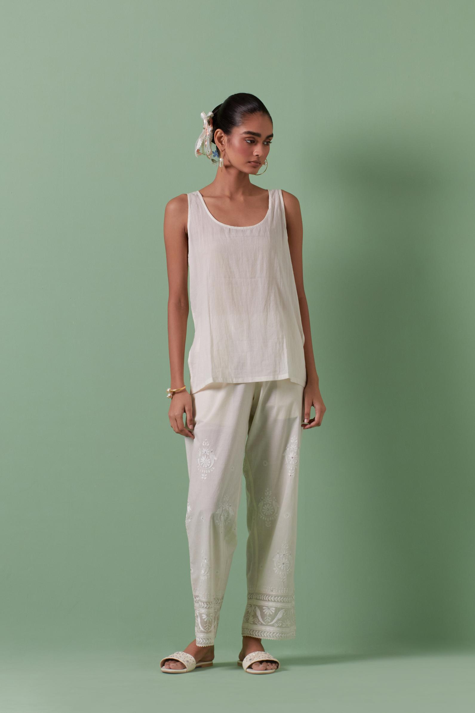 Off-white cotton chanderi embroidered short top with 3/4th sleeves, paired with off white cotton straight pants with all over off white color embroidery detailed with sequins.