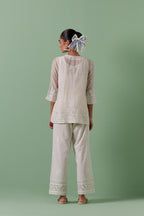 Off-white cotton chanderi embroidered short top with 3/4th sleeves, paired with off white cotton straight pants with all over off white color embroidery detailed with sequins.