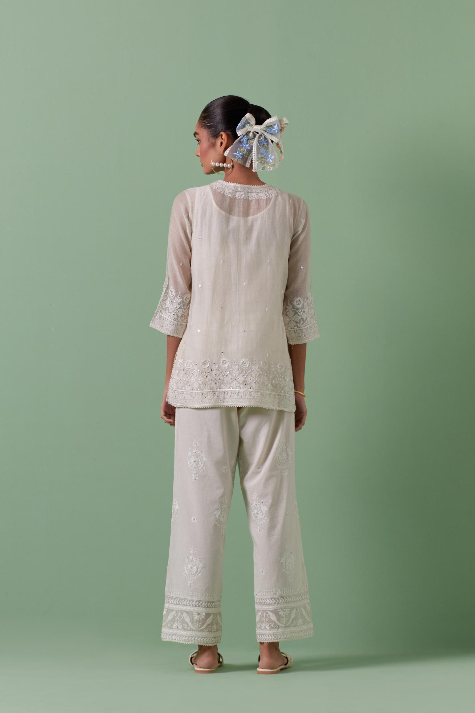 Off-white cotton chanderi embroidered short top with 3/4th sleeves, paired with off white cotton straight pants with all over off white color embroidery detailed with sequins.