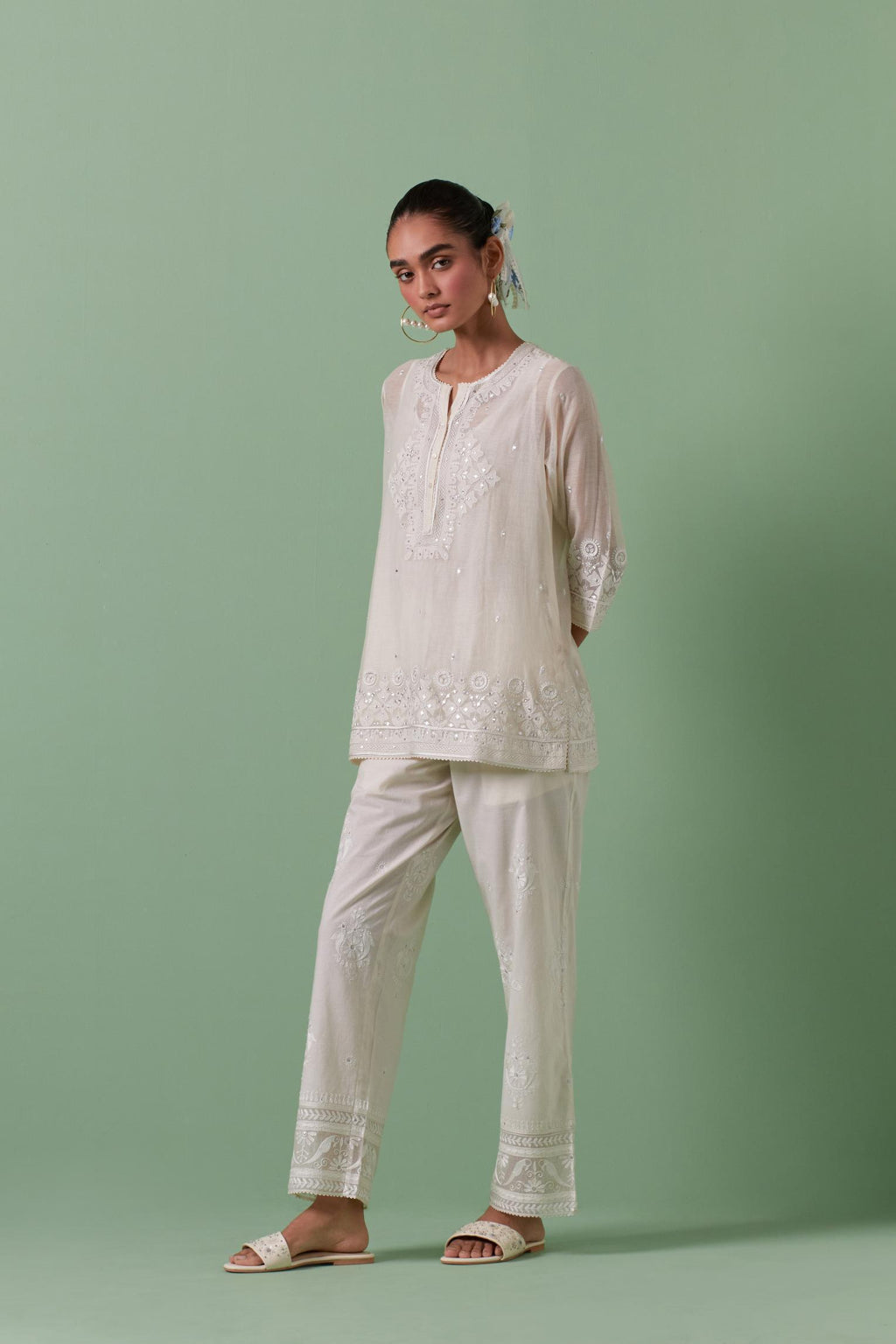 Off-white cotton chanderi embroidered short top with 3/4th sleeves, paired with off white cotton straight pants with all over off white color embroidery detailed with sequins.