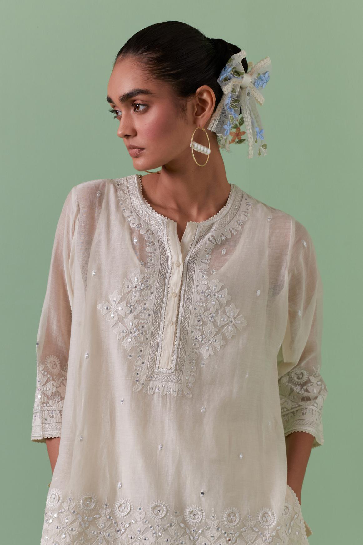 Off-white cotton chanderi embroidered short top with 3/4th sleeves, paired with off white cotton straight pants with all over off white color embroidery detailed with sequins.