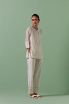 Off-white cotton chanderi embroidered short top with 3/4th sleeves, paired with off white cotton straight pants with all over off white color embroidery detailed with sequins.