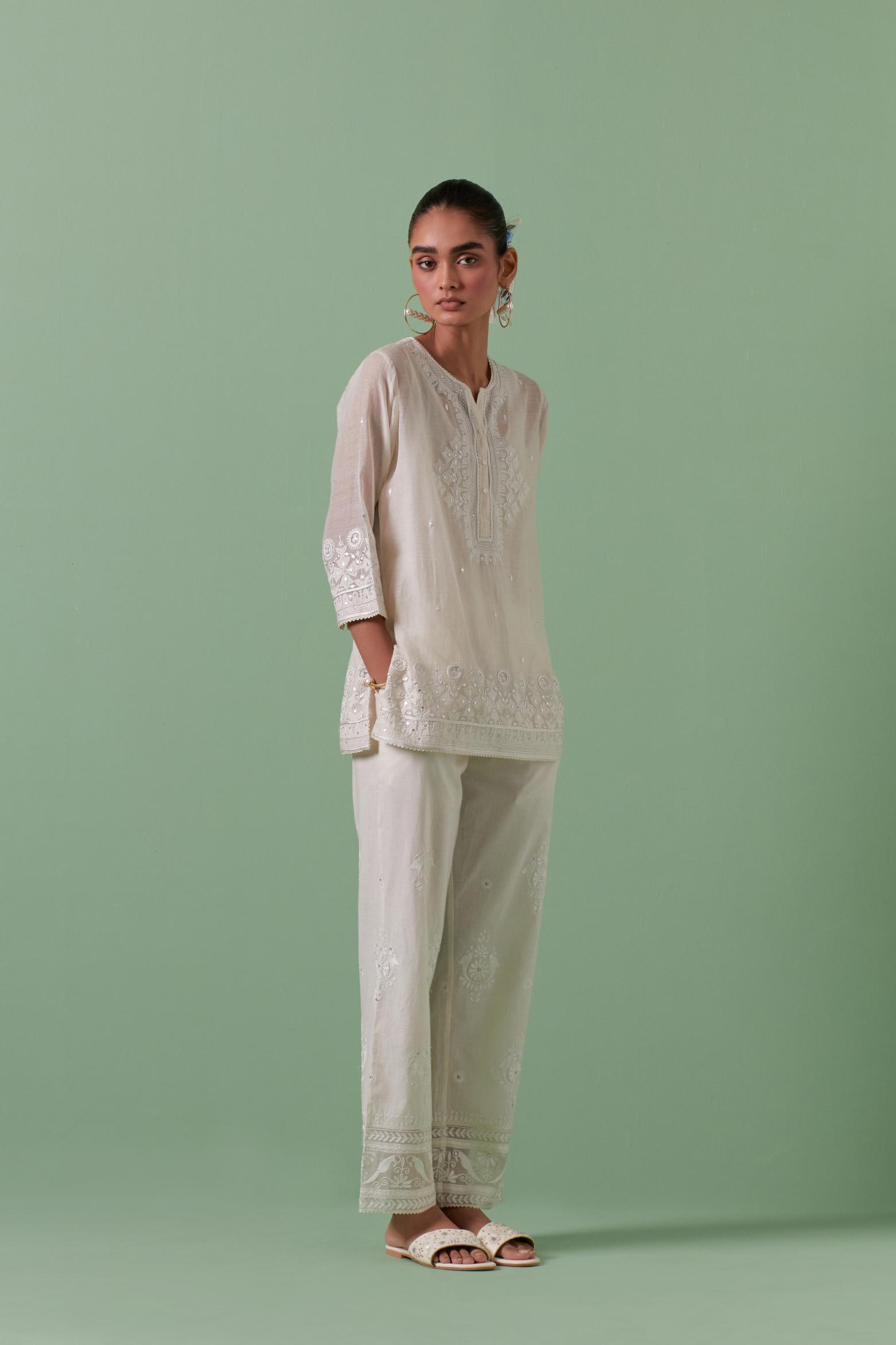 Off-white cotton chanderi embroidered short top with 3/4th sleeves, paired with off white cotton straight pants with all over off white color embroidery detailed with sequins.