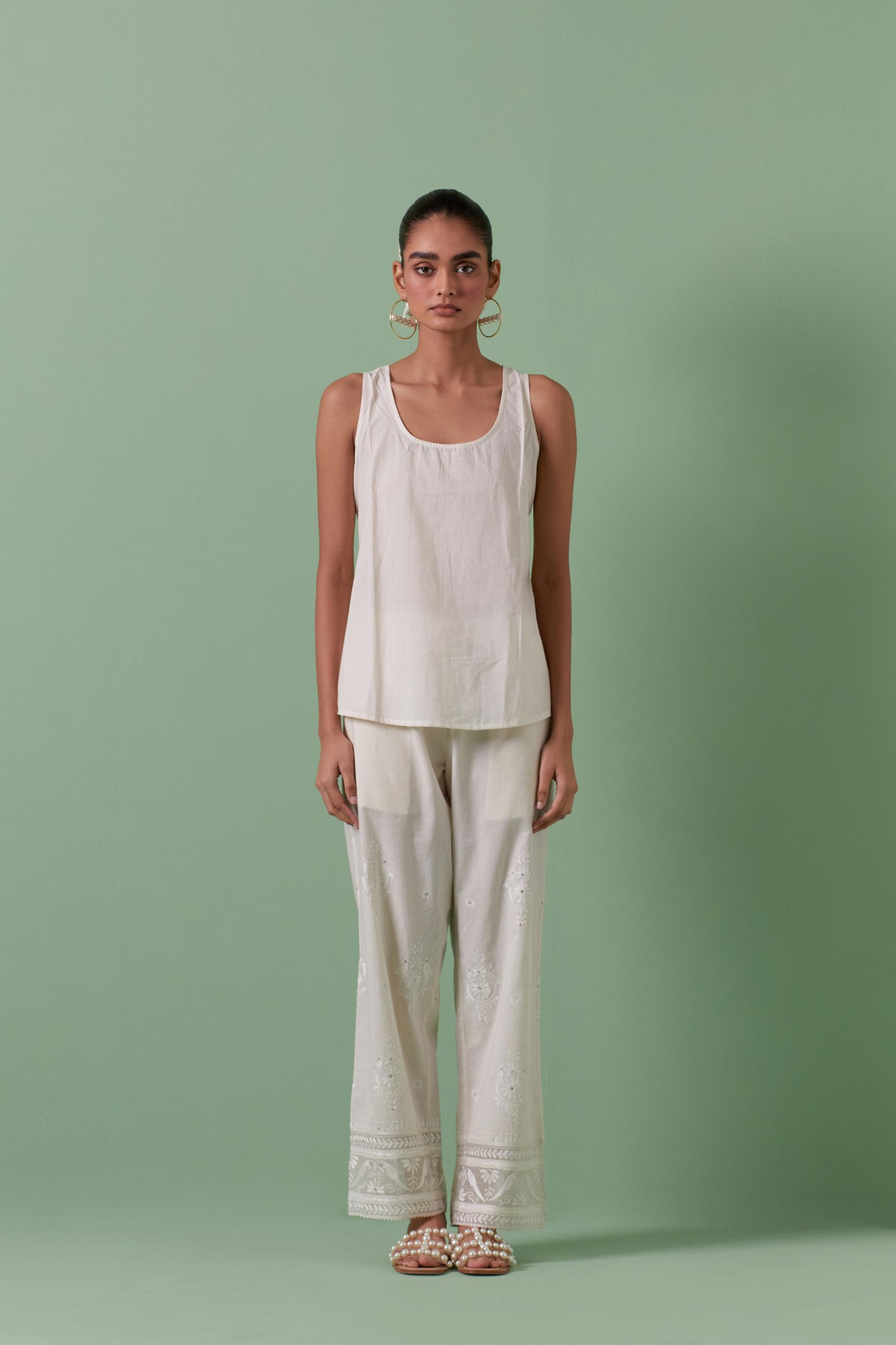 Off-white cotton chanderi embroidered short top with 3/4th sleeves, paired with off white cotton straight pants with all over off white color embroidery detailed with sequins.