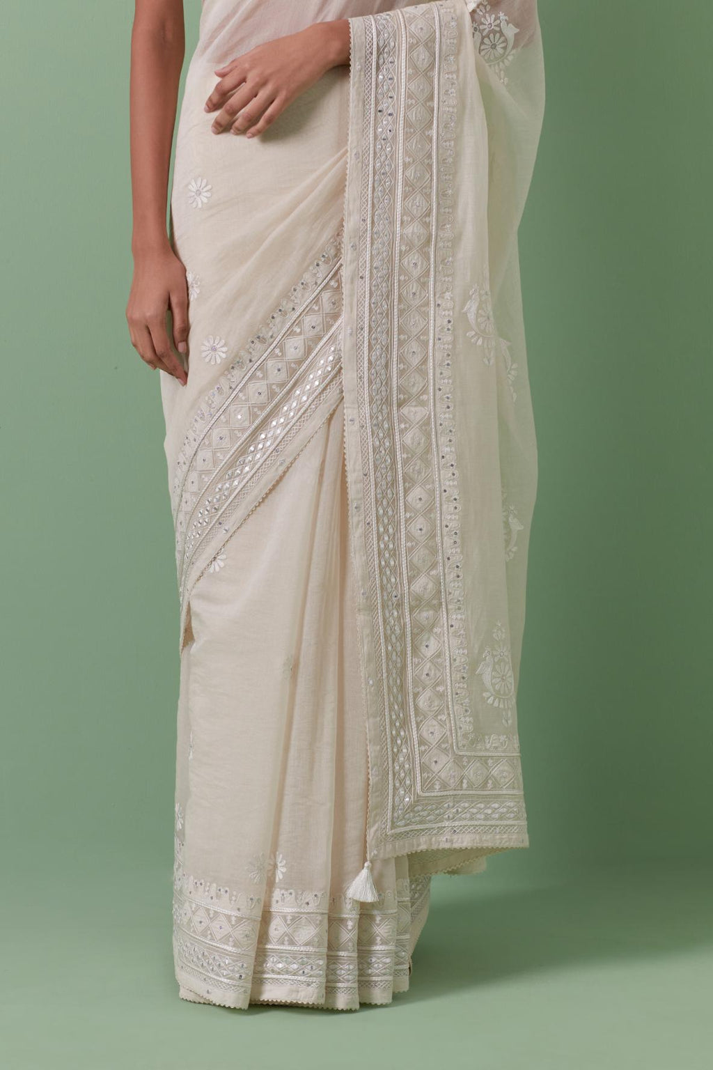 Off-white cotton chanderi saree with delicate silk thread embroidery, highlighted with braids, mirrors and sequins, paired with off white cotton chanderi embroidered blouse with deep round neck and princess seams.